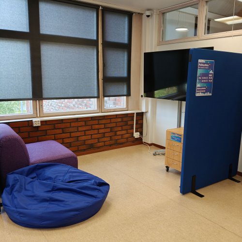 Kuva pelinurkasta. Violetti nojatuoli, sininen säkkituoli ja televisio.