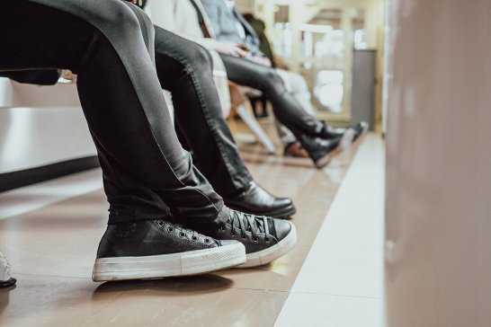 Penkillä istuvien ihmisten jalkoja.