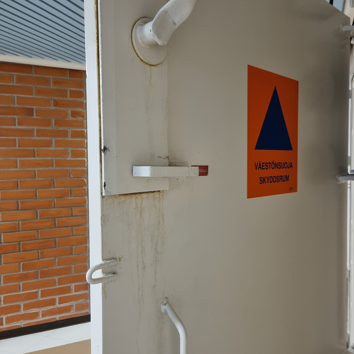 Väestönsuojat on merkitty kansainvälisellä tunnuksella, joka on sininen kolmio oranssilla taustalla.
