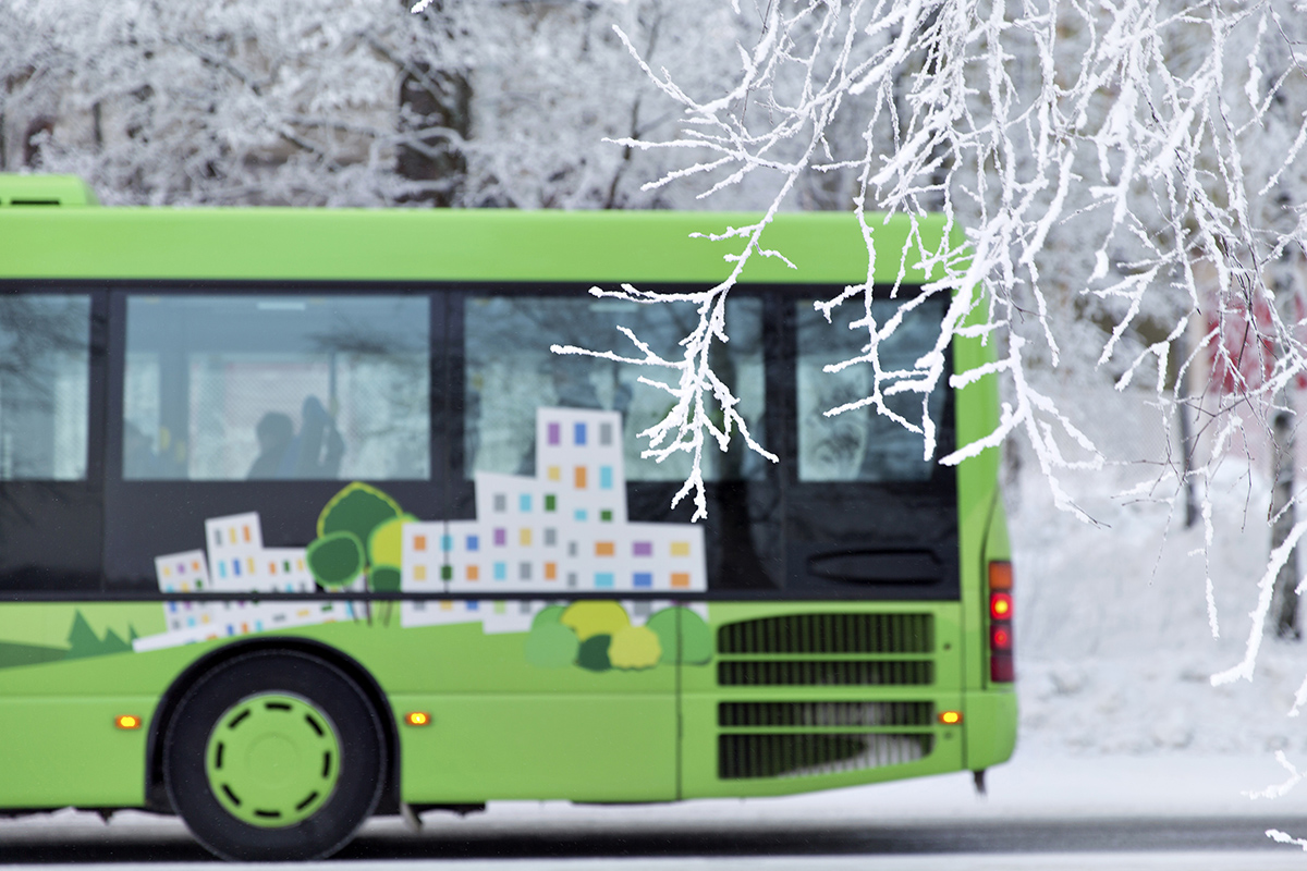 Vihreä bussi talvisessa maisemassa.