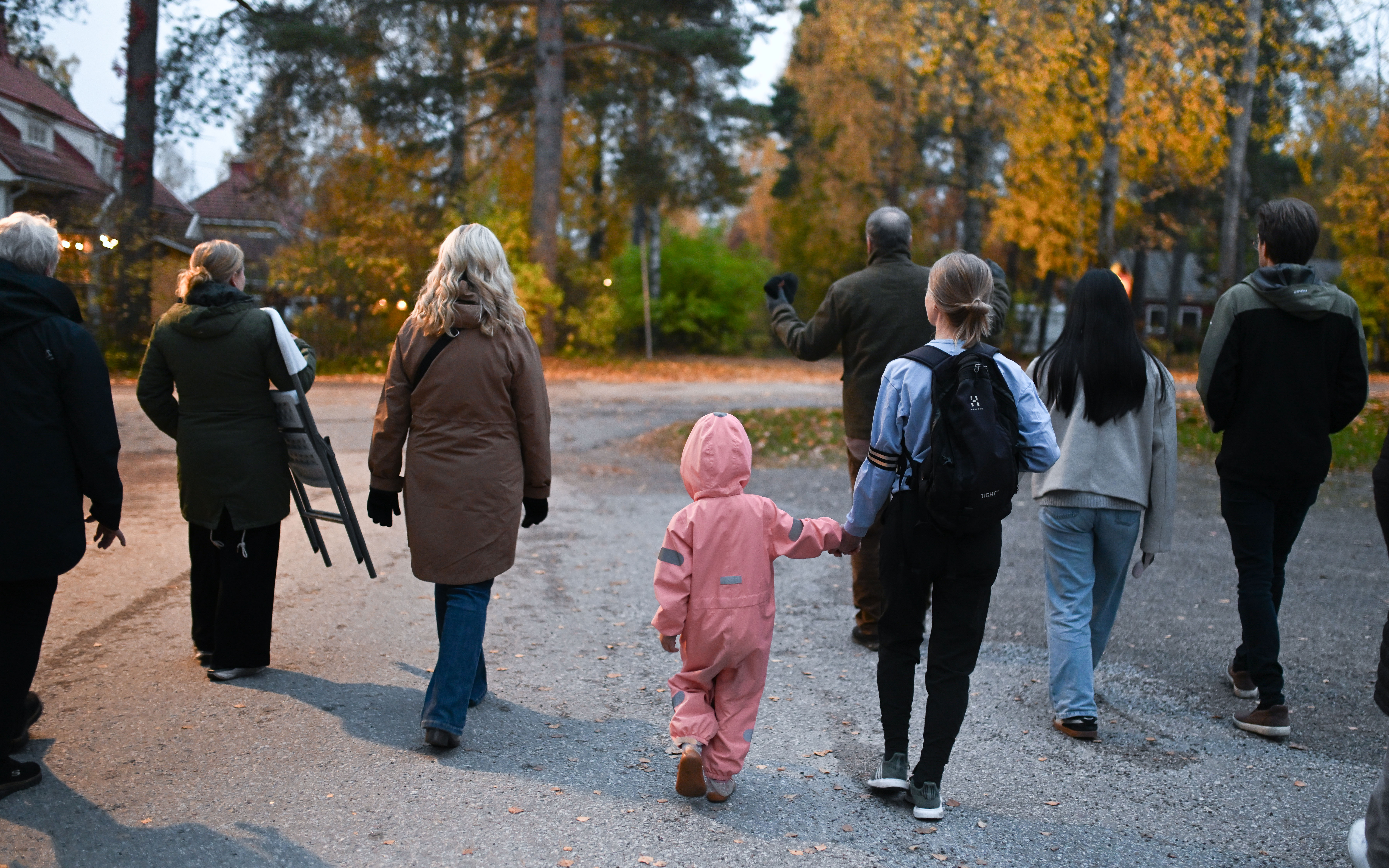 Ihmisiä kävelemässä syksyisessä katukuvassa. Kuva otettu kävelijöiden takaa.